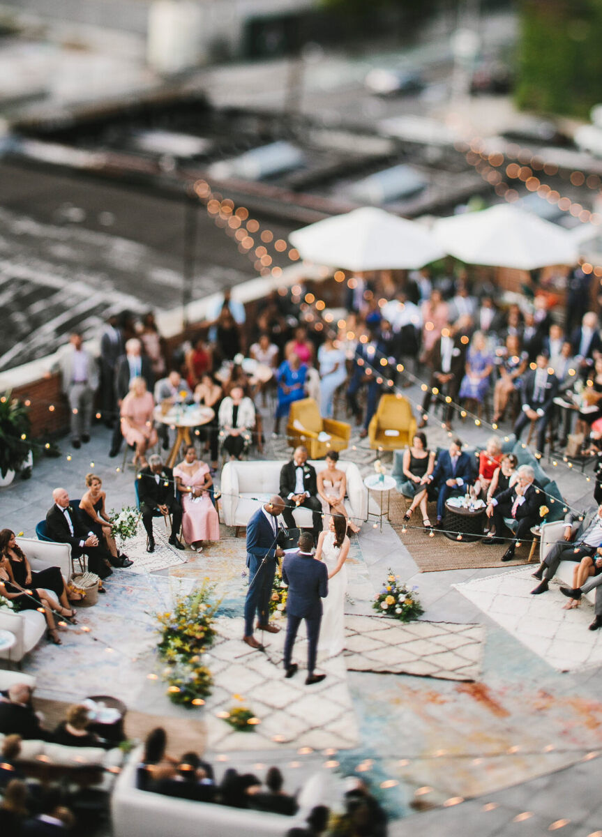 Wedding Aisle: A drone shot of a couple getting married with guests surrounded them and various rugs laid out around them.