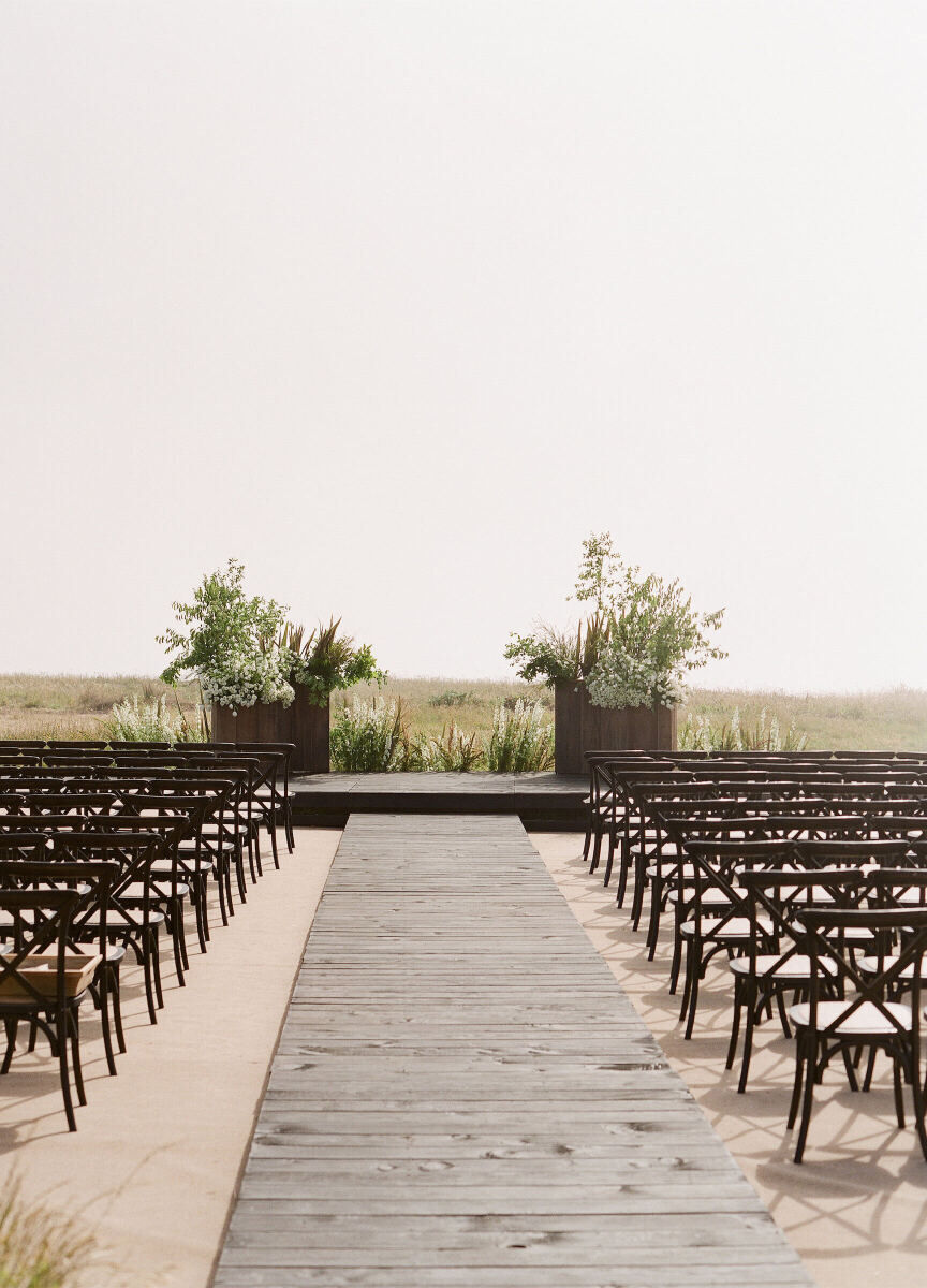 Wedding Aisle: A wooden wedding aisle leading up to an elevated altar with arrangements of greenery on either side.