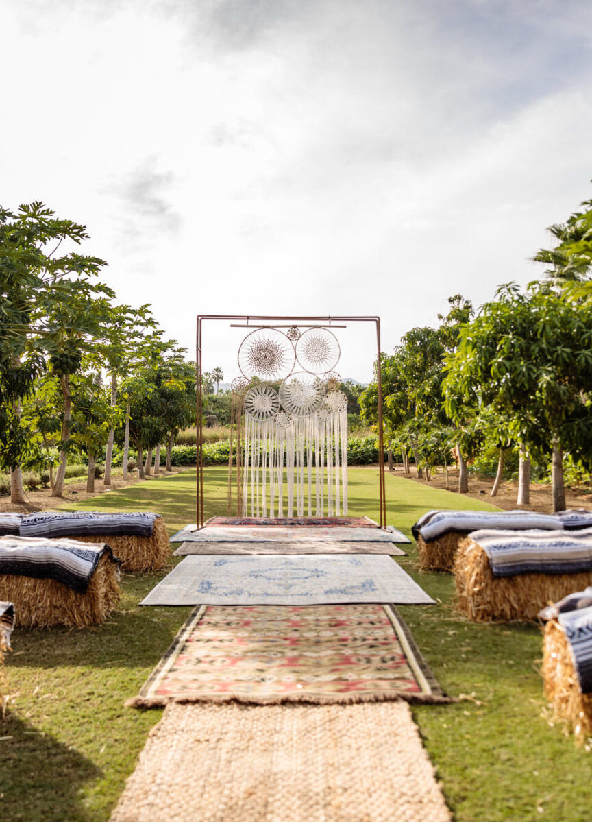 Wedding Aisle: Mismatched rugs serve as the runner for this outdoor ceremony with hay bales as seats.