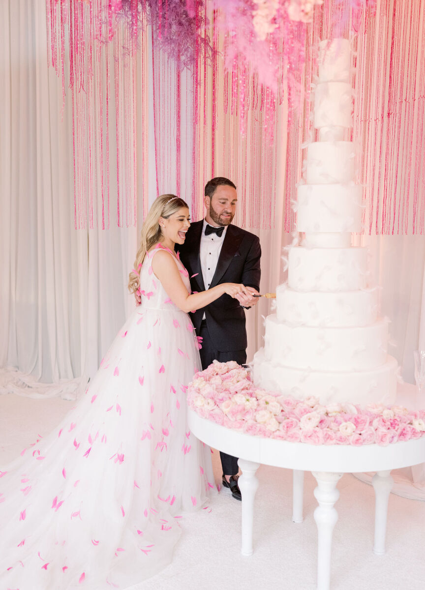 Wedding cake bakery: A couple cuts a tall tiered wedding cake. 