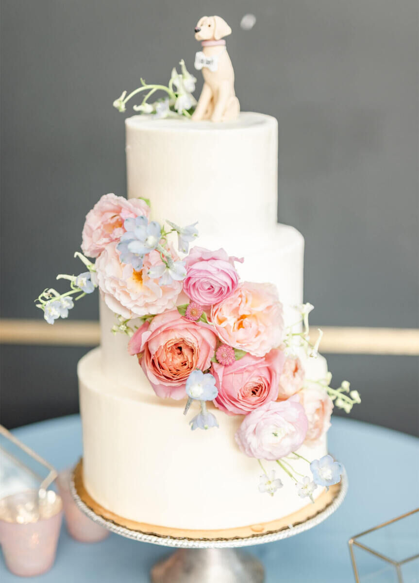 Wedding cake bakery: tiered wedding cake with flowers and a dog cake topper. 