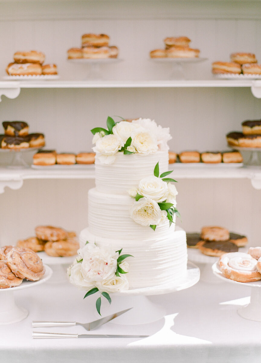 Wedding cake bakery: textured, white wedding cake with other dessert options in the background. 