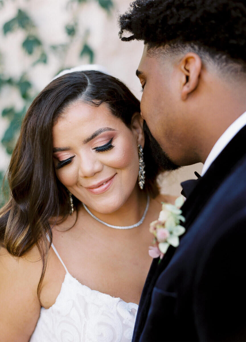 Wedding details: A groom about to kiss a bride on her cheek.