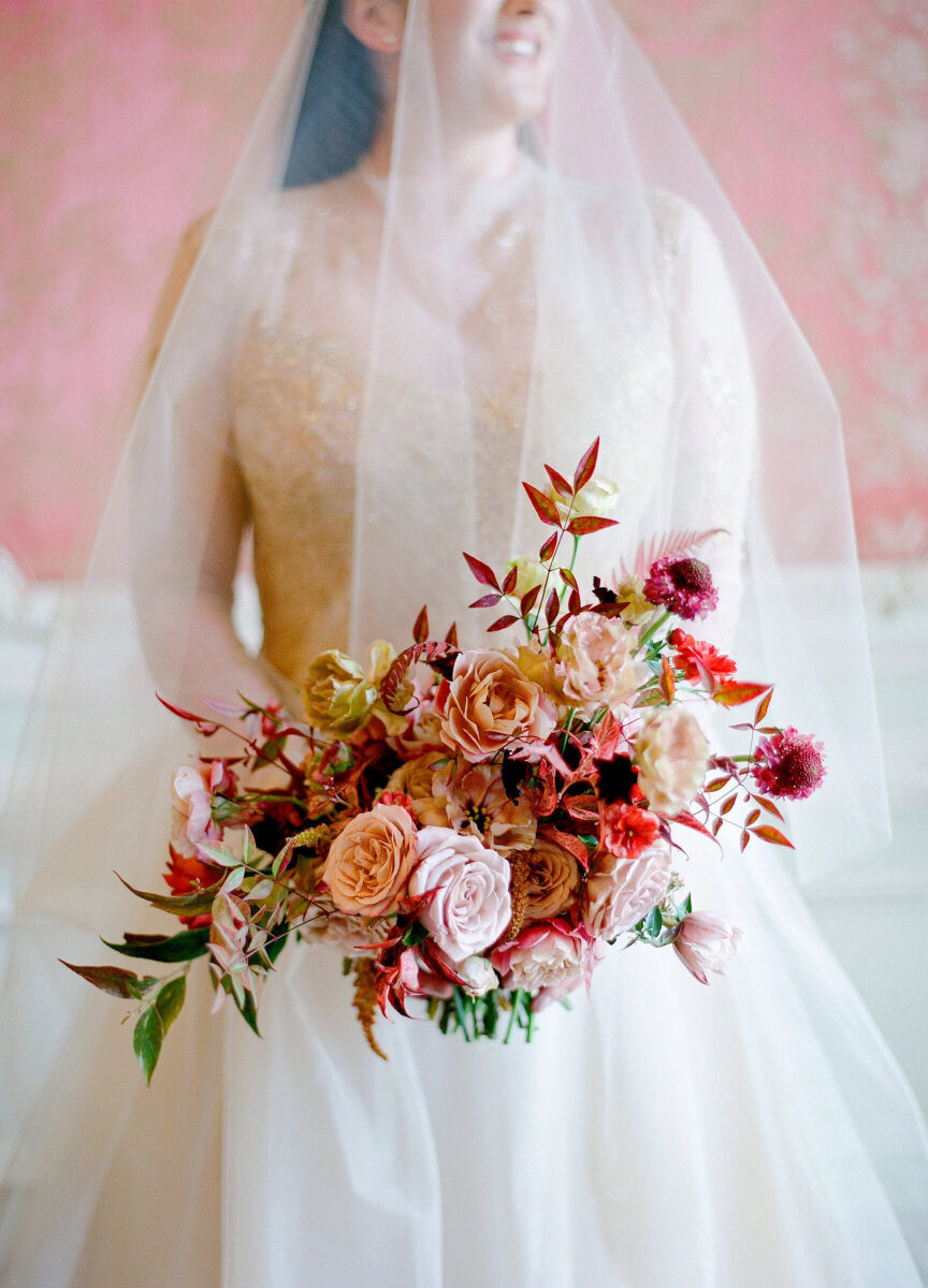 Wedding details: an asymmetrical wedding bouquet held by a bride in a veil