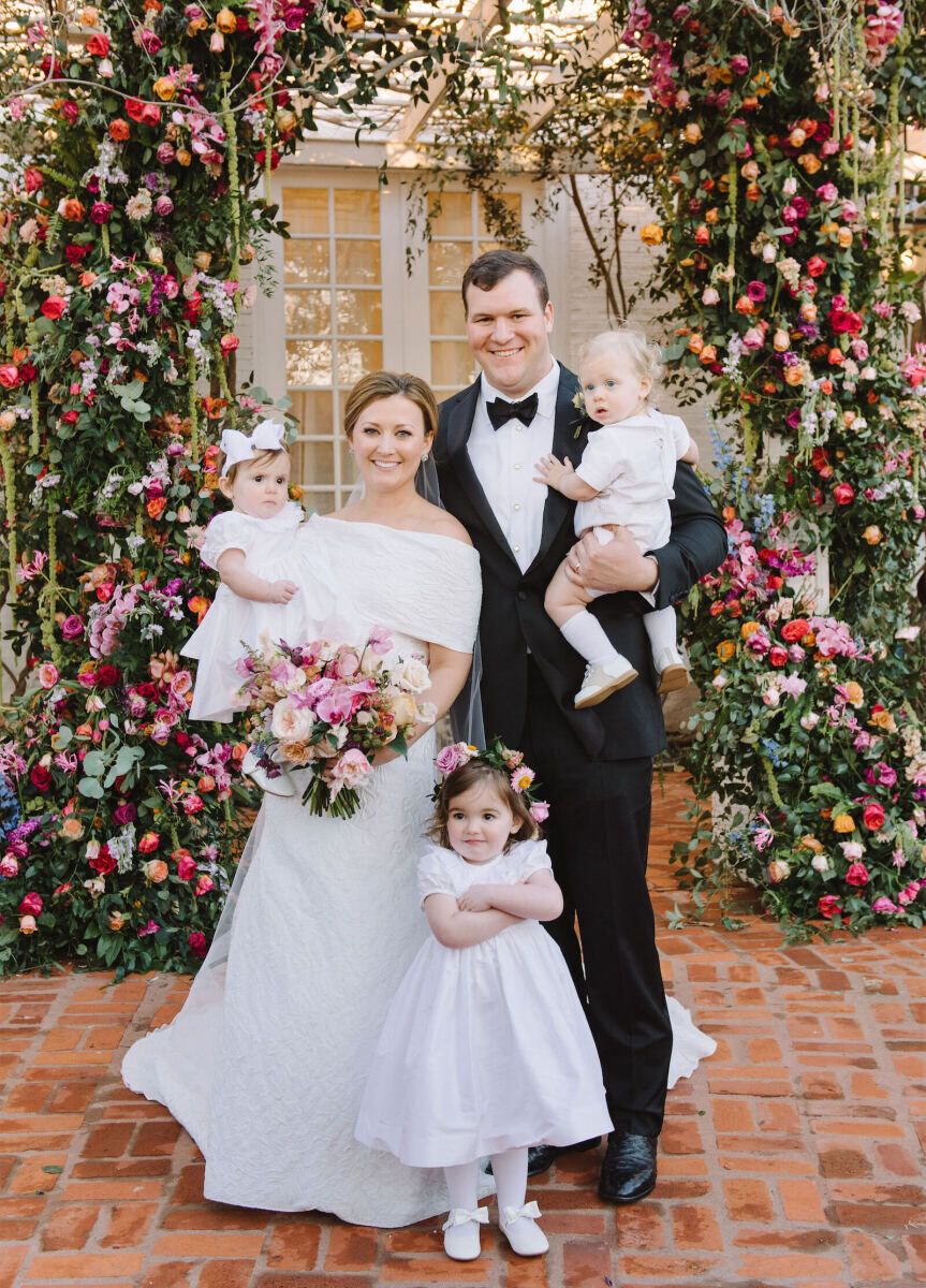 A bride and groom hold a trio of young children that were in their wedding party.