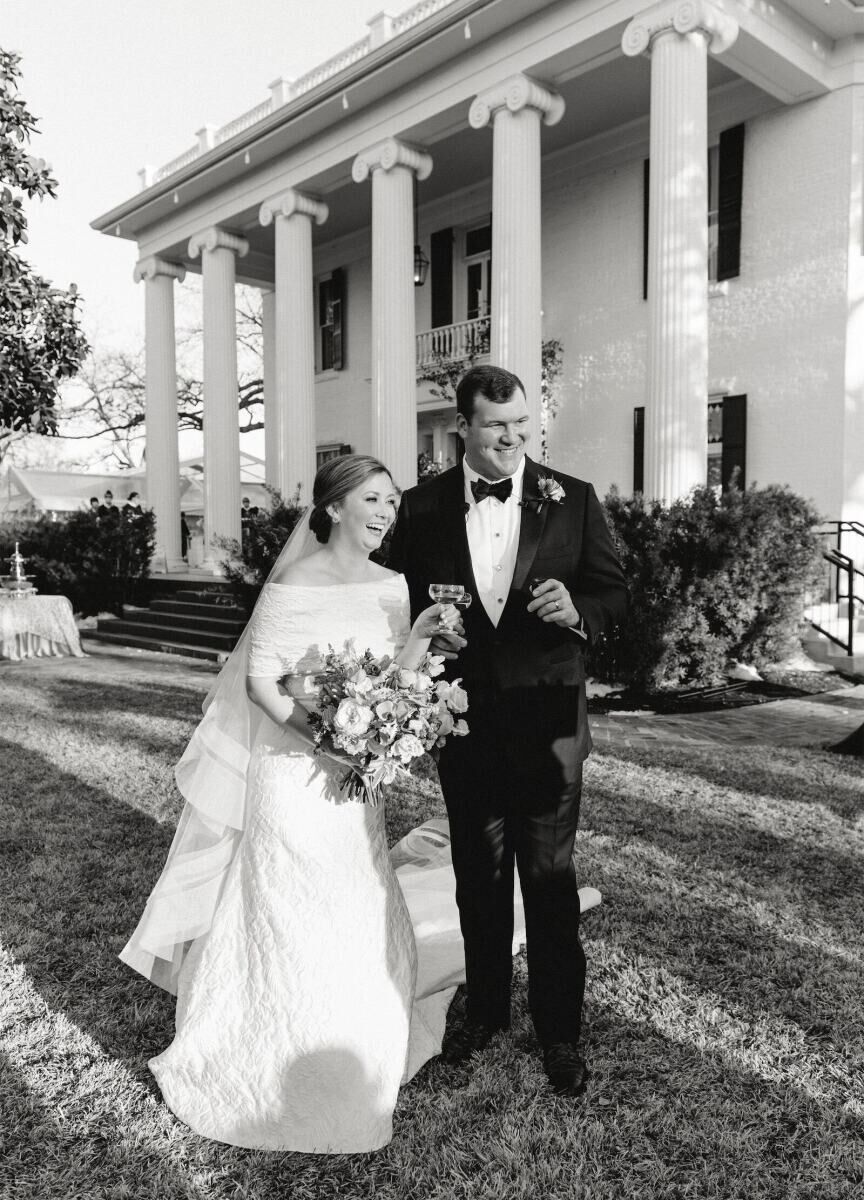 A newlywed bride and groom share a laugh and sip Champagne on the lawn of the wedding venue, a mansion near Austin, Texas.