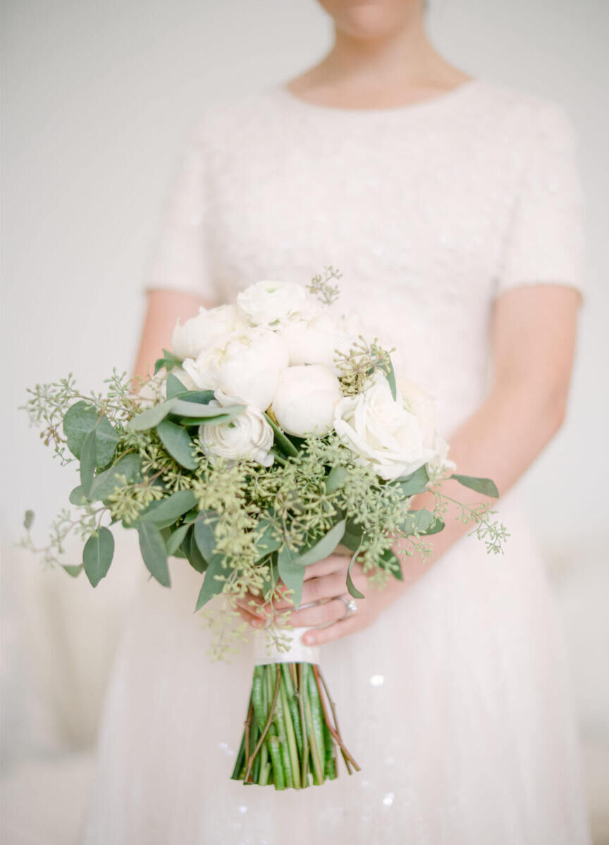 Wedding details: Bride holding white and green wedding bouquet featured centerpieces with eucalyptus