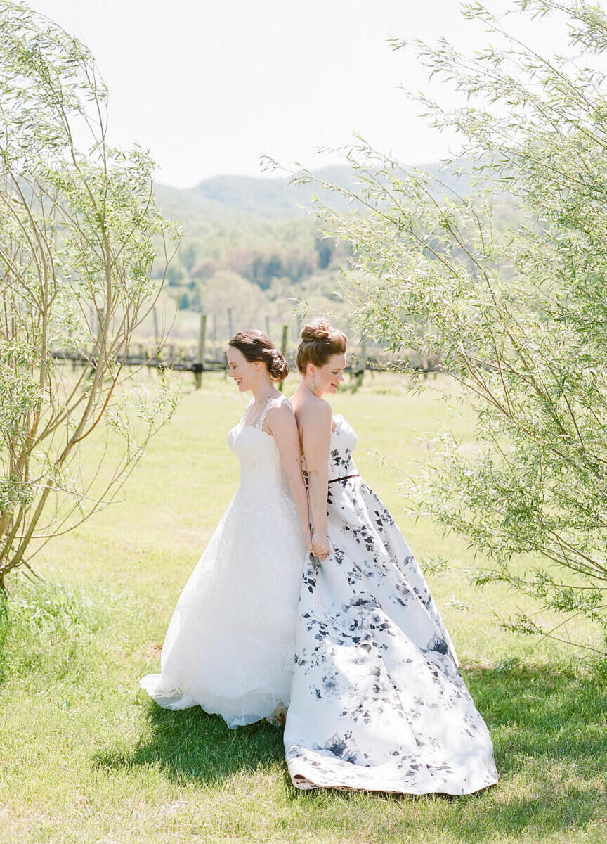 Wedding Dress Shopping: Two brides holding hands with their backs facing each other on a farm in Virginia.