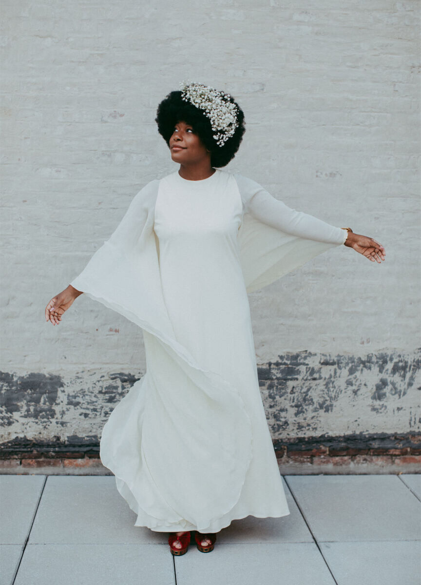 Wedding Dress Shopping: A bride twirling in a long-sleeve, floor-length gown with white florals decorating her hair.