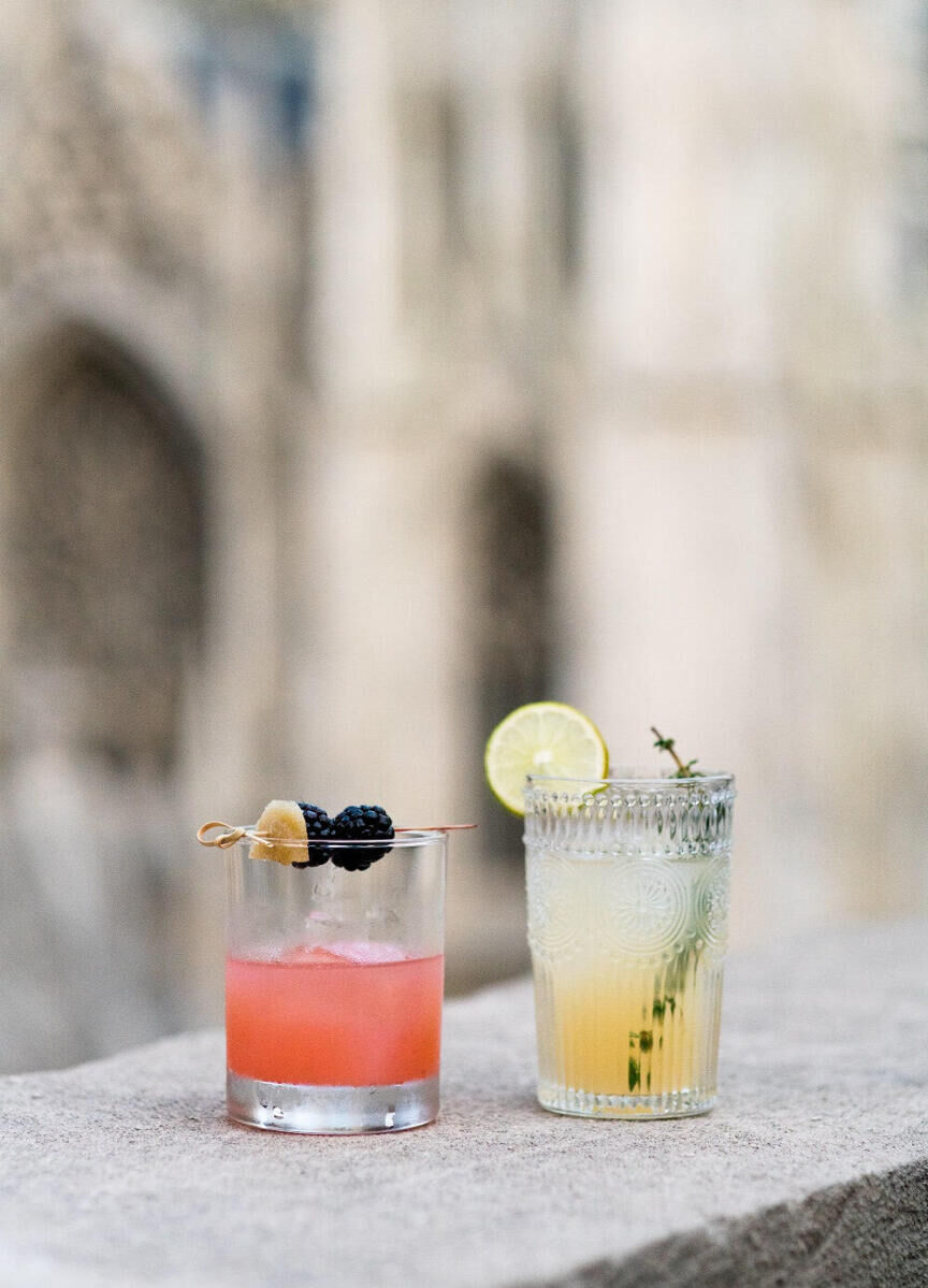 Wedding Drinks: Two drinks, one pink and one yellow with fruit garnishes, on a ledge.