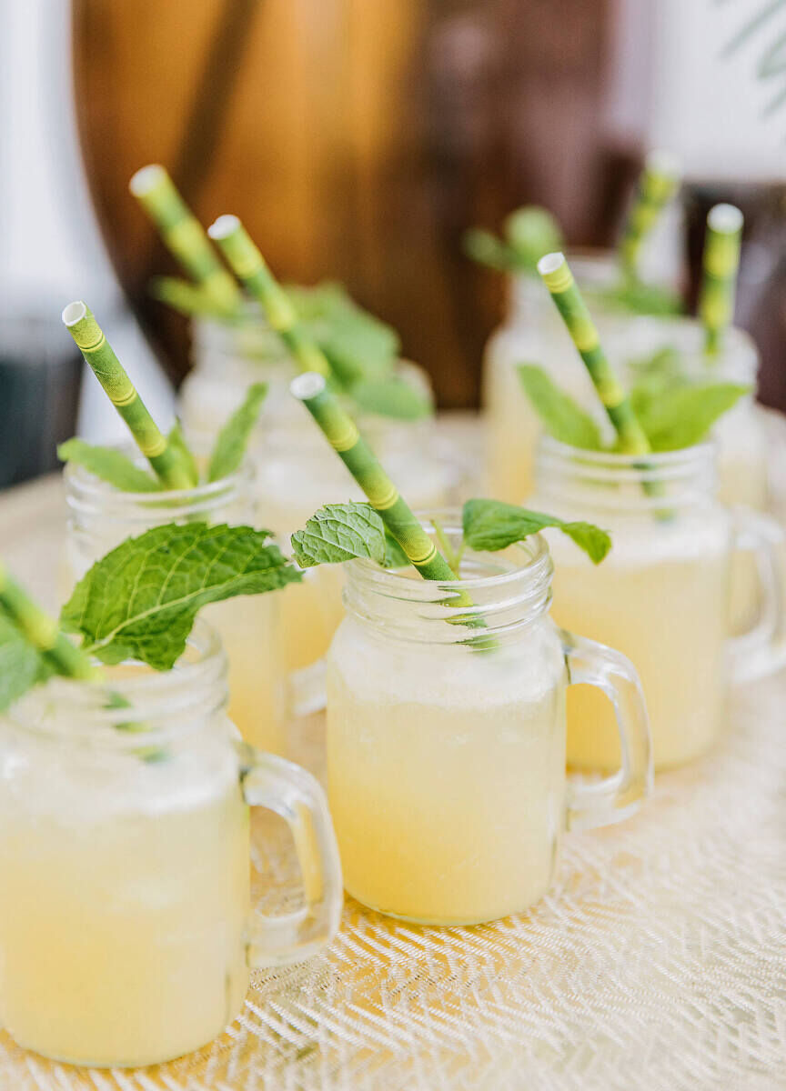 Wedding Drinks: Mai Tai cocktails in glasses with handles, green bamboo straws and mint garnishes.