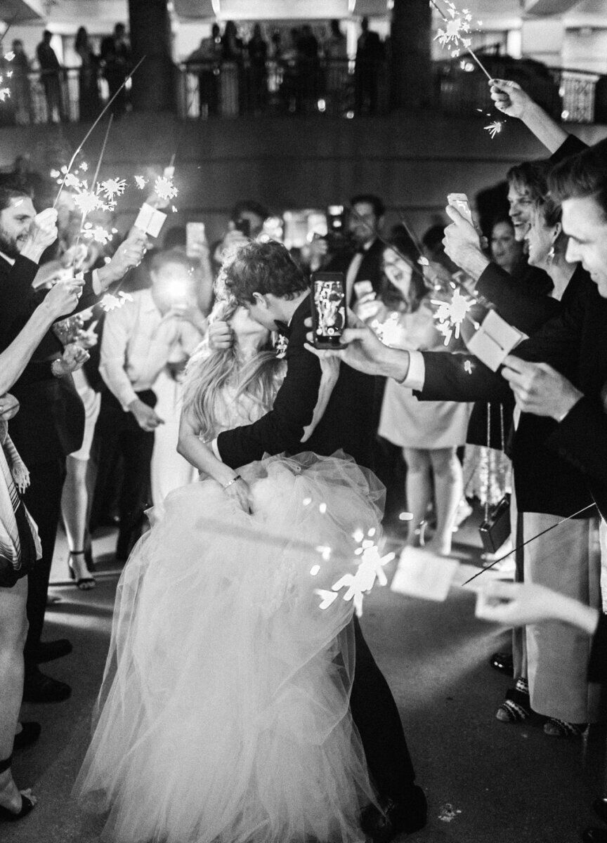 Wedding Fireworks Wedding Sparklers: A wedding couple kissing in front of their guests, who are all holding sparklers.