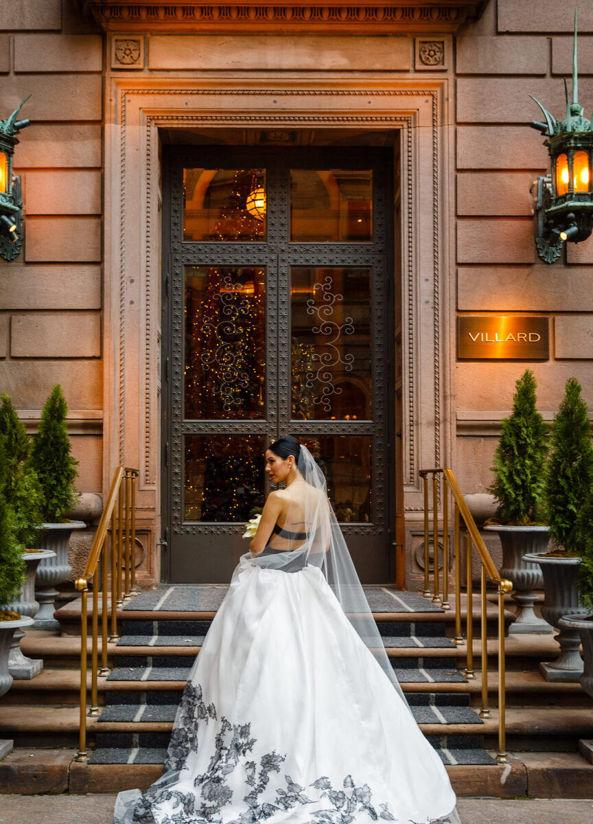 Wedding Photography Ideas: A bride wearing a white gown with black accents, turning her back to the camera while standing on an outdoor staircase.