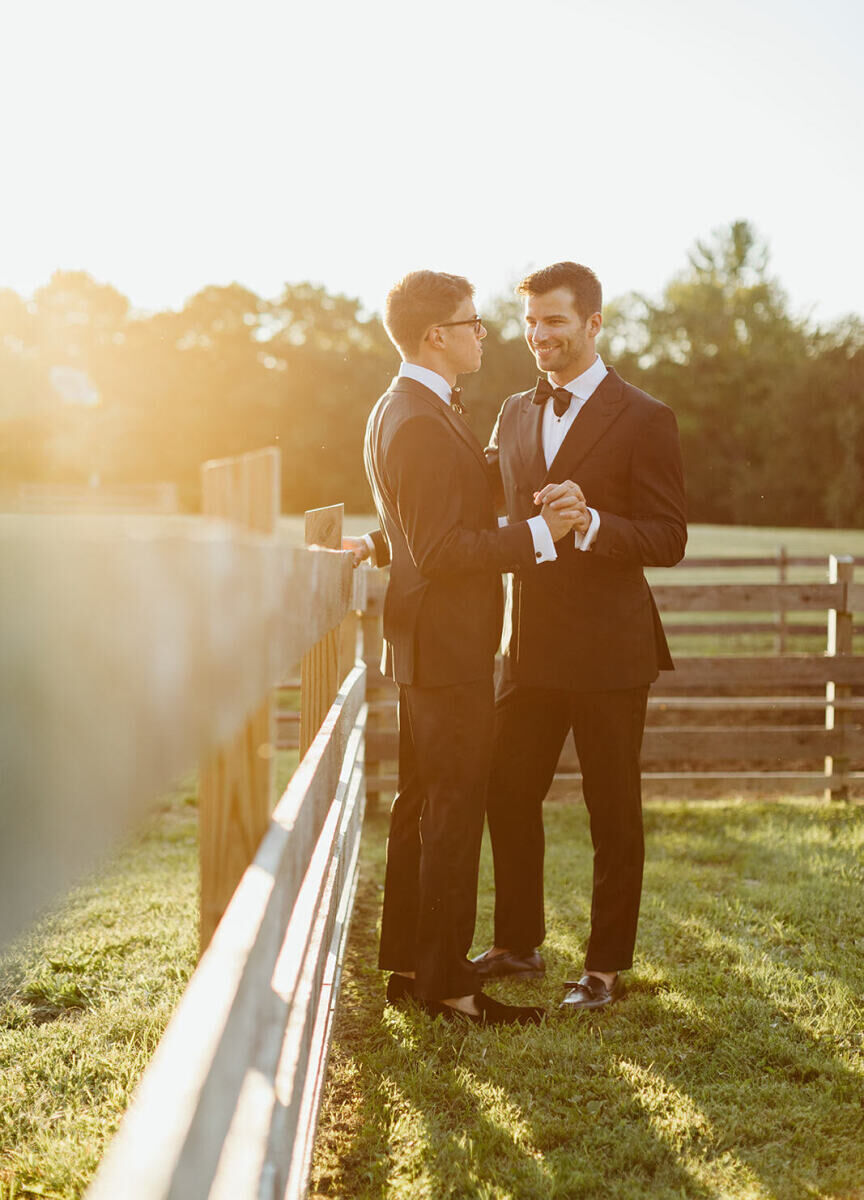 Wedding Photography Ideas: Two grooms holding hands on a farm as the sun is setting in New York.