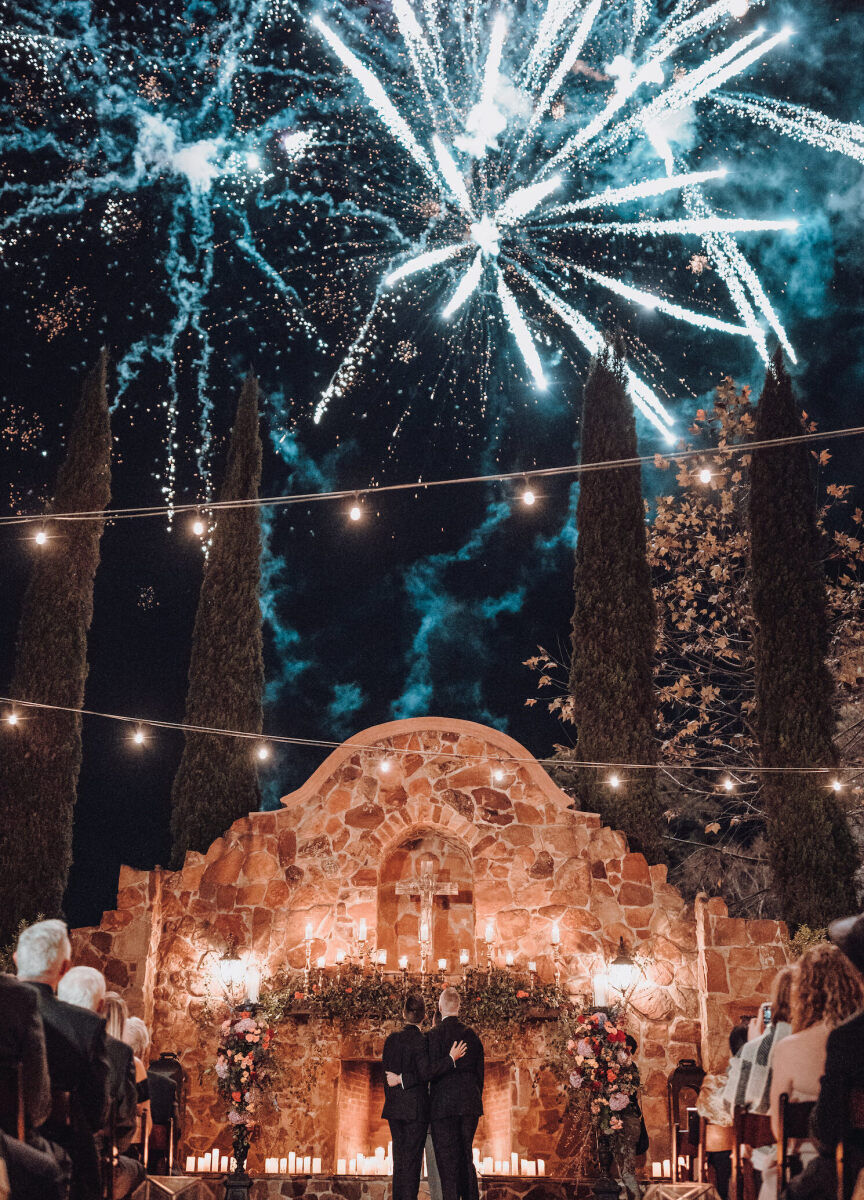 Wedding Photography Ideas: Two grooms and their guests looking out at fireworks overhead in Texas.