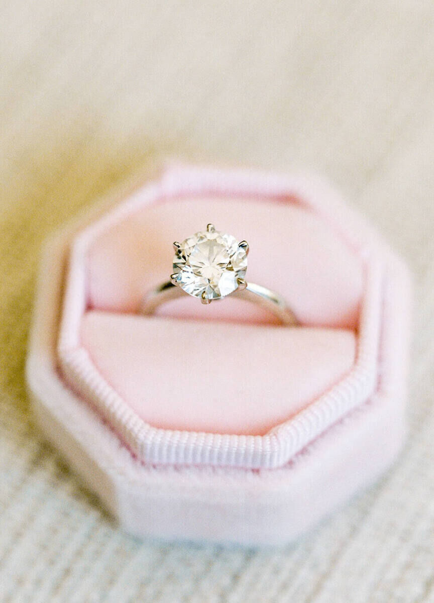 Wedding Ring Design: A round-cut engagement ring sitting in a pink octagonal ring box.