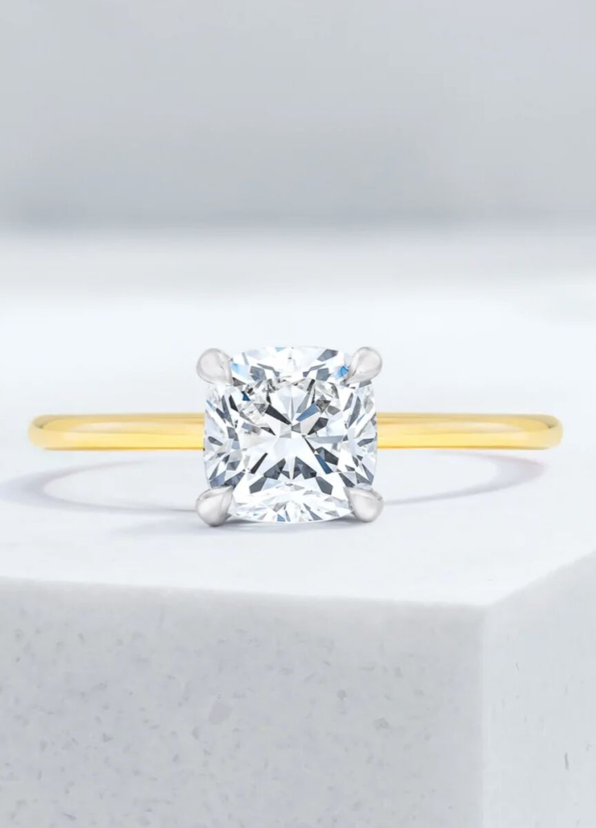 Wedding Ring Design: A cushion cut diamond ring with a yellow gold band.