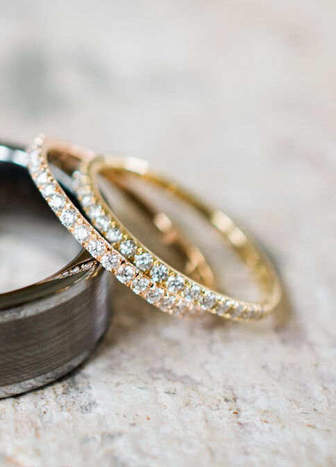 Wedding Ring Design: Gold and pink pavé wedding bands resting against a large metal wedding band.