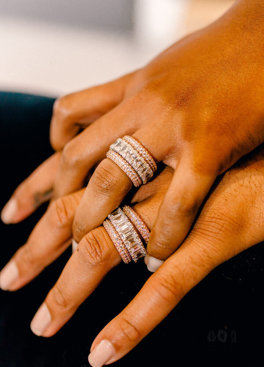 Wedding Ring Design: Two hands holding one another with matching eternity and pavé wedding bands.