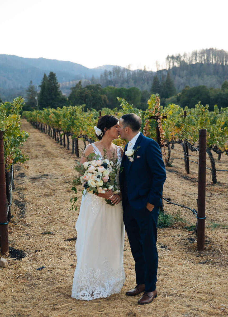 Wedding Venues in California: A wedding couple kissing near a vineyard in Napa Valley.