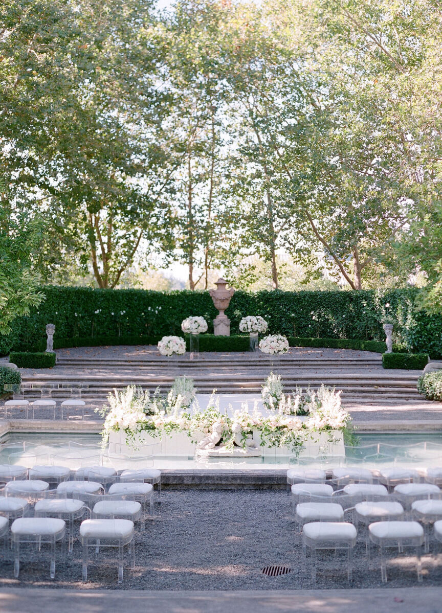 Wedding Venues in California: An outdoor ceremony setup with backless, cushioned seats and several floral arrangements in a garden setting.