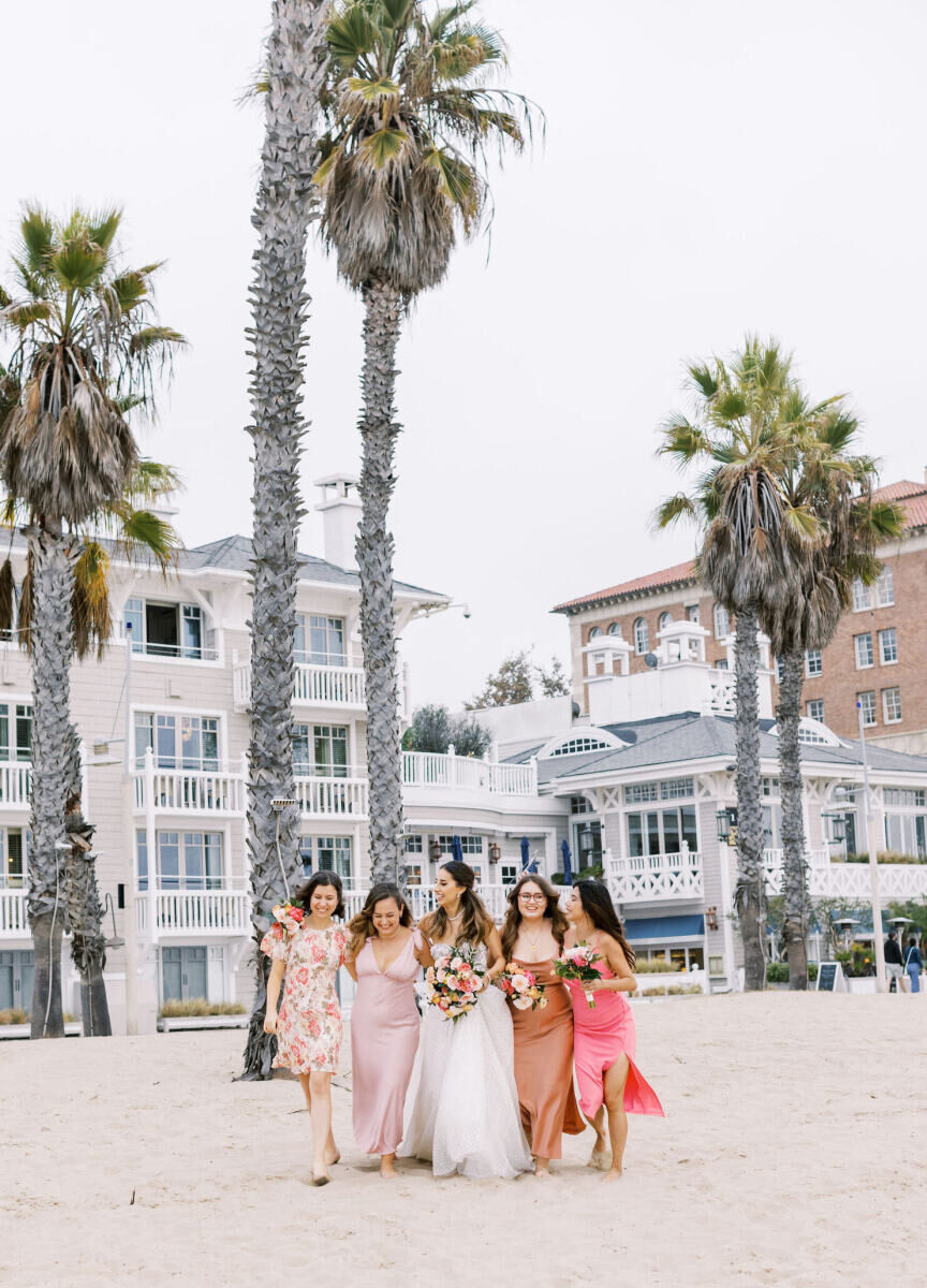 Wedding Venues in California: A bride walking on the beach with her four bridesmaids dressed in different shades of pink.