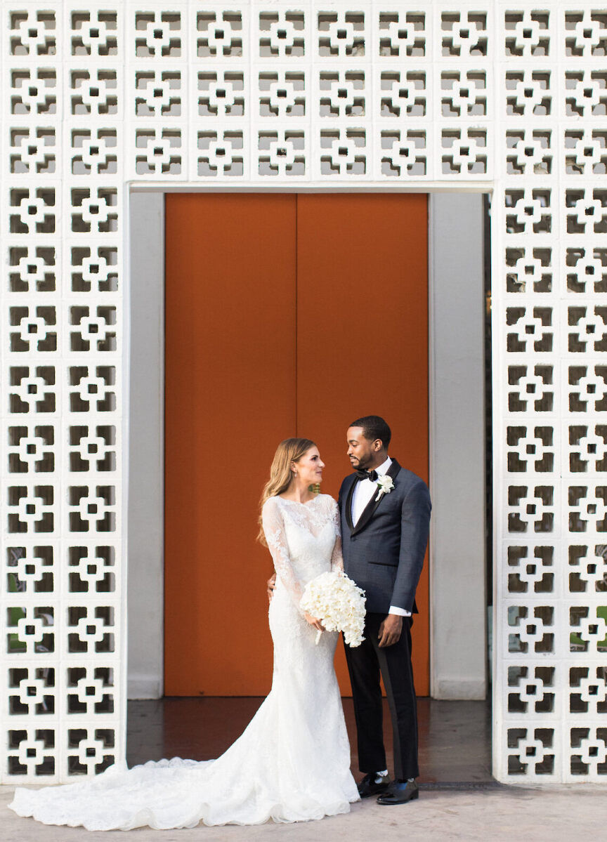 Wedding Venues in California: A wedding couple staring at each other near a modern, white-walled lobby in Palm Springs.