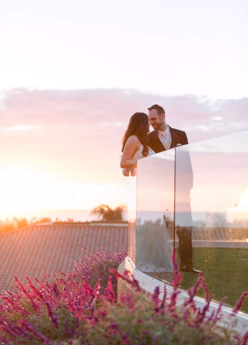 Wedding Venues in California: A wedding couple leaning on a glass lookout point in Carlsbad, California.