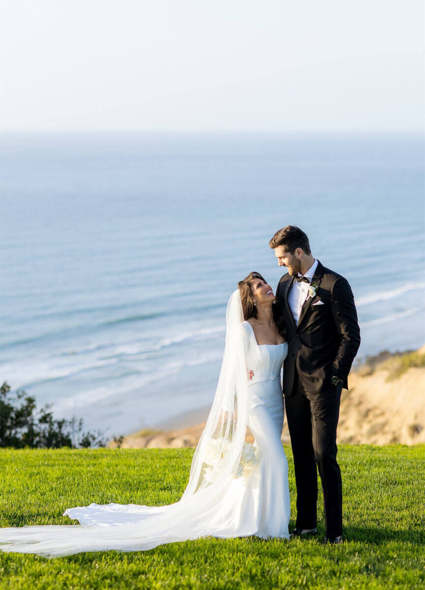 Wedding Venues in California: A wedding couple smiling at each other on a bluff overlooking the ocean in La Jolla, California.