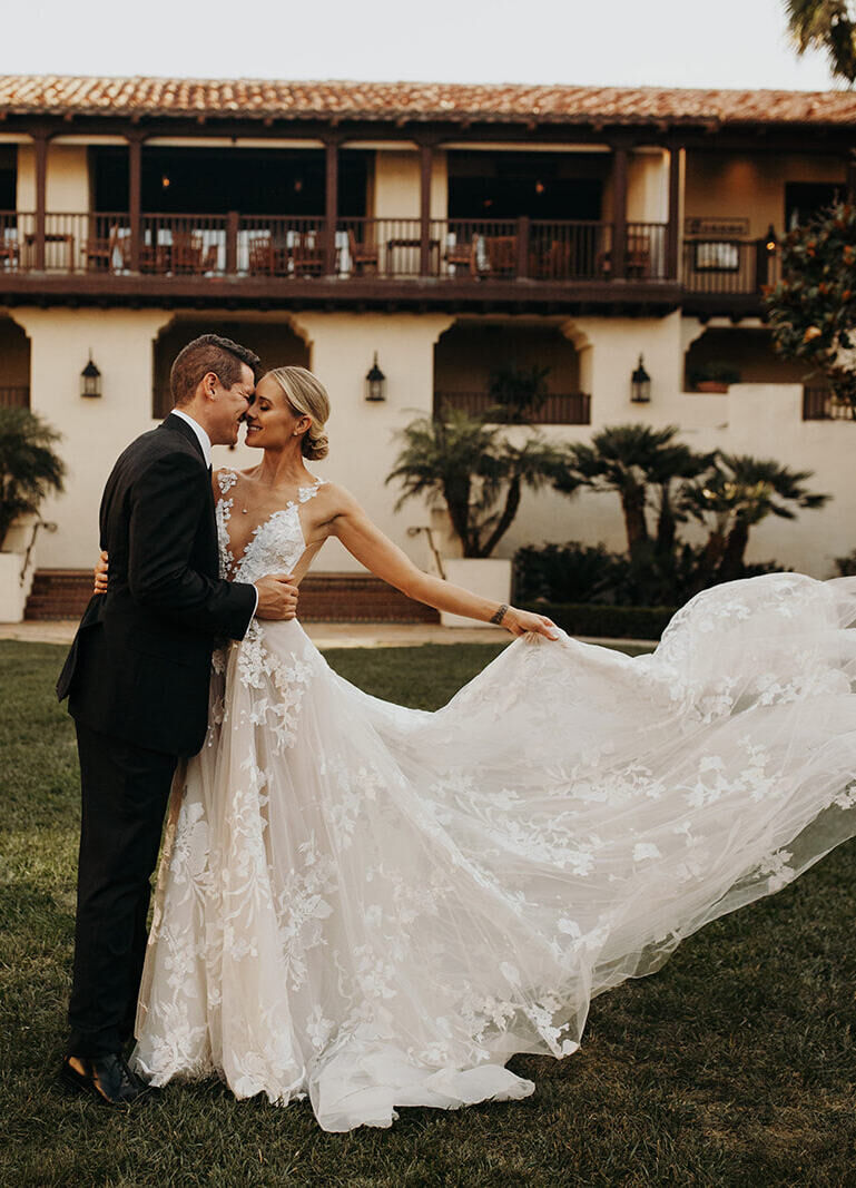 Wedding Venues in California: A wedding couple smiling at each other as the bride lets her train blow with the wind.