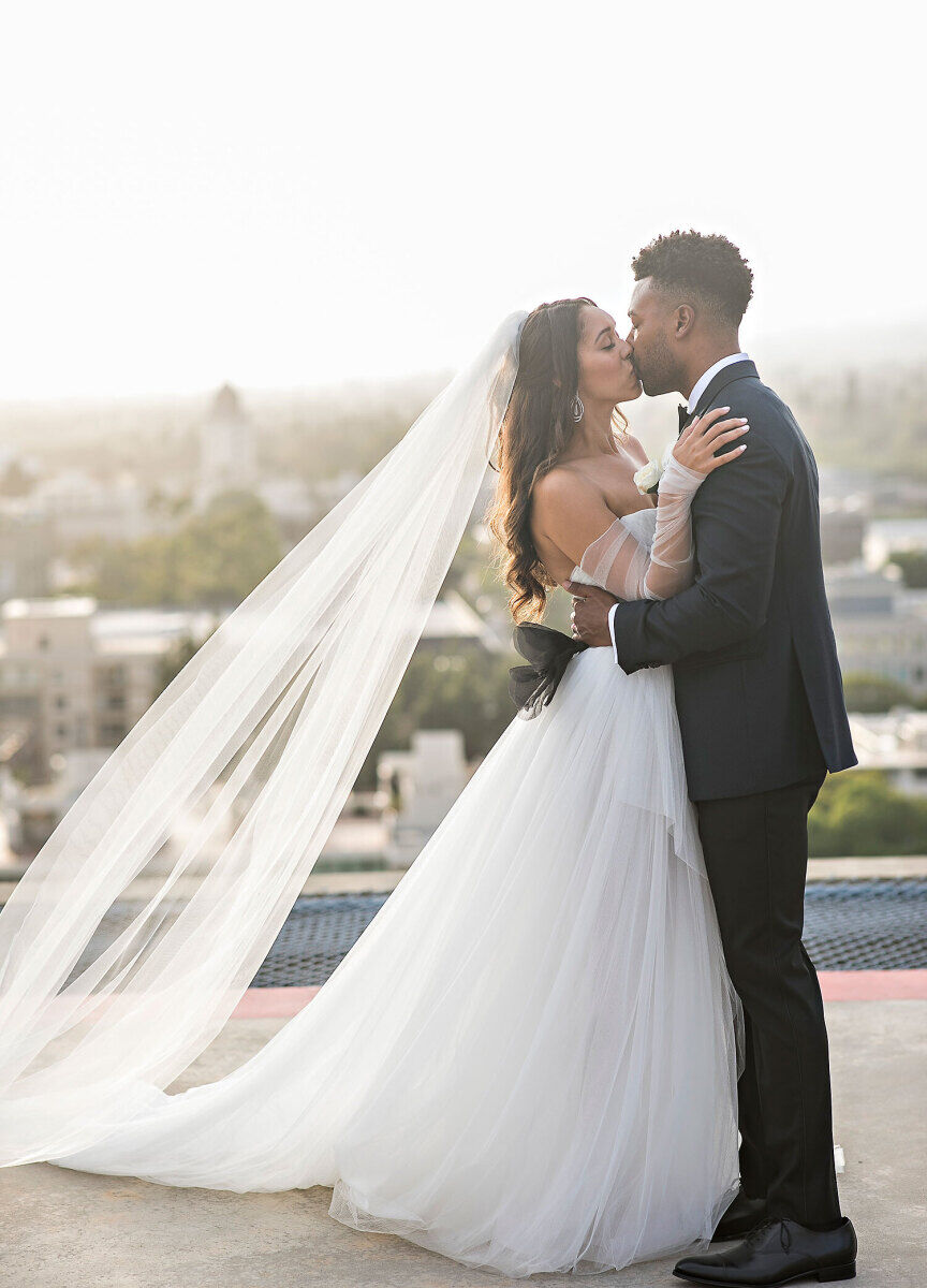 Wedding Venues in California: A wedding couple kissing on a rooftop in Los Angeles.