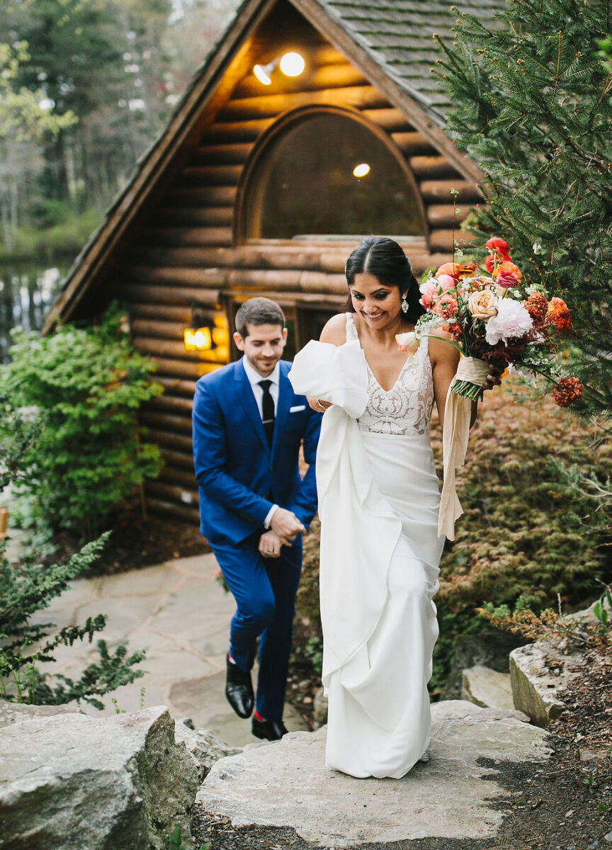 Wedding Website Examples: A wedding couple walking on stones and away from a wood cabin.