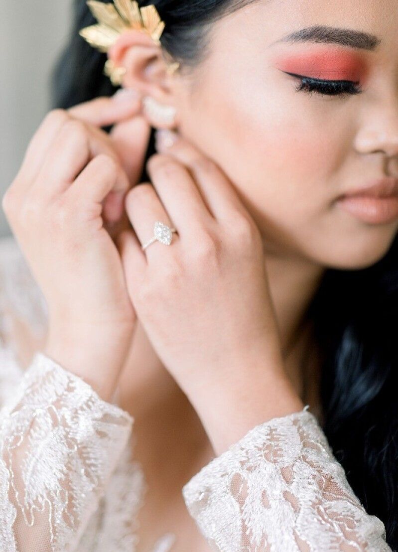 Wedding Website Examples: A bride putting on her earring on her wedding day.