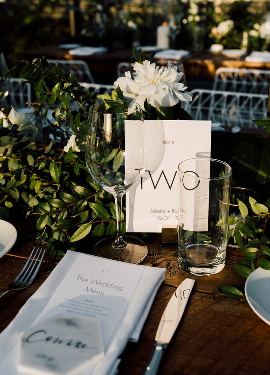 Wedding Website Examples: A reception table with greenery and white florals and the table 