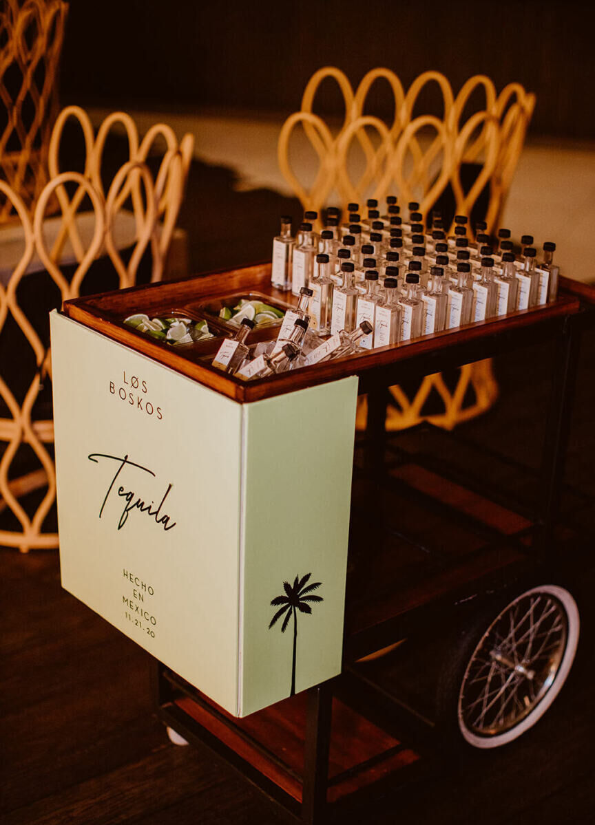 A cart holding mini bottles of tequila was customized with a couple's palm tree motif and their last name.