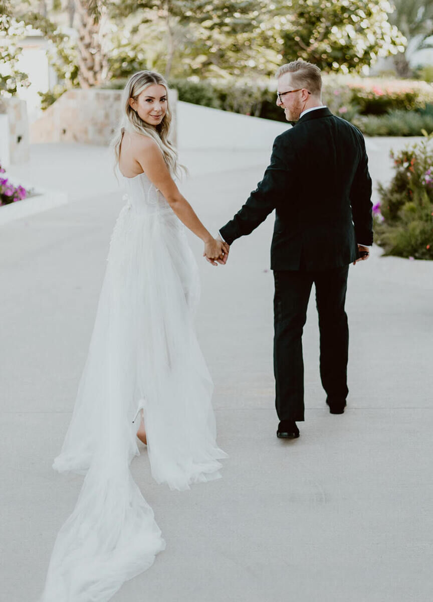 A bride and groom walk a path at Chileno Bay Resort, in Mexico, on their wedding day.