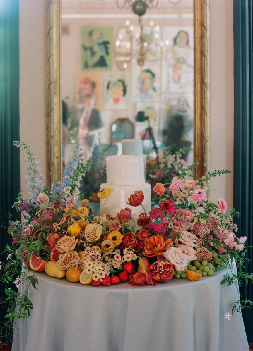 A rainbow of flowers and fruit surrounded a small wedding cake at a whimsical wedding reception in New Orleans.