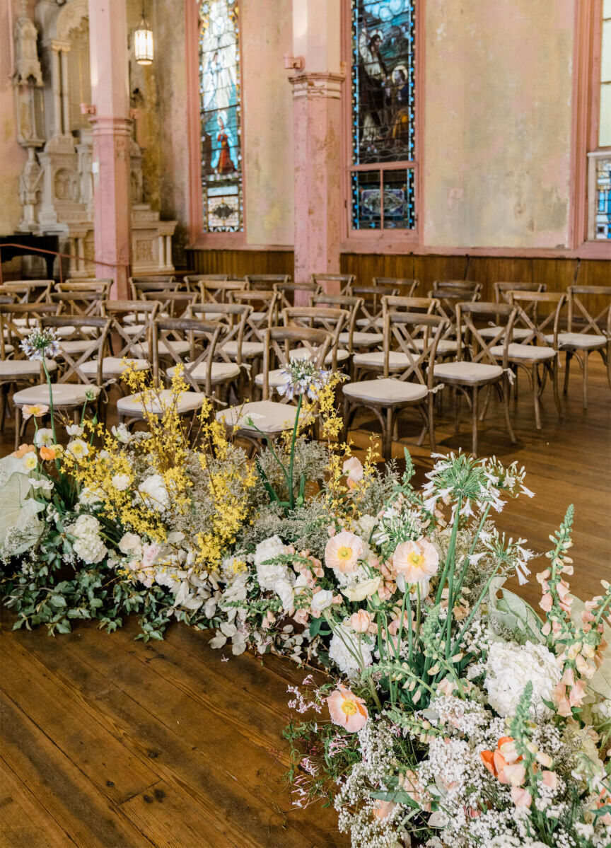 For this whimsical wedding in a former church, a low, pastel floral semi-circle was built for the couple to stand in the middle of.