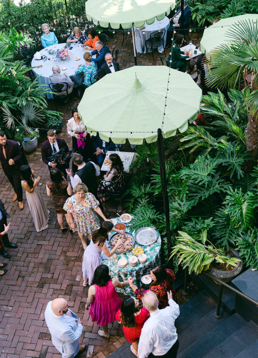 Bistro lights and green umbrellas dressed up the cocktail hour space at a whimsical wedding reception in New Orleans.