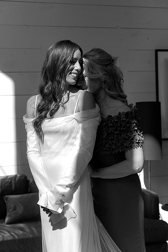 Bride portrait in a black and white wedding portrait, wearing an off-the-shoulder long-sleeve tulle gown by window light indoors