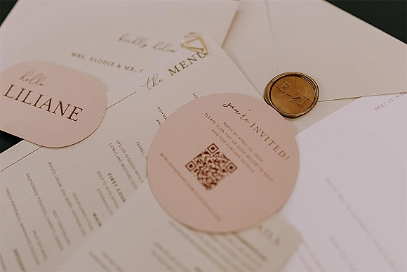 Invitation suite wedding invitation flat lay with round cards, cream envelopes, monogram wax seal, gold foil text, on dark tabletop