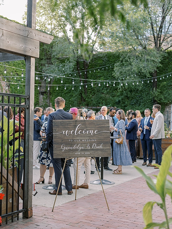 Wedding welcome sign on an easel, a wood wedding welcome sign with calligraphy lettering under string lights in a courtyard