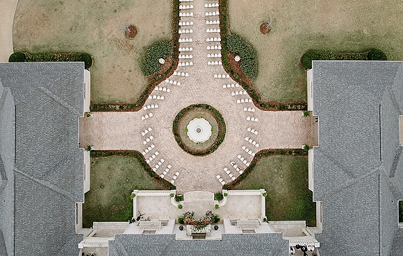 Ceremony seating layout with outdoor ceremony seating around a circular fountain, white chairs on pavers framed by hedges in a courtyard