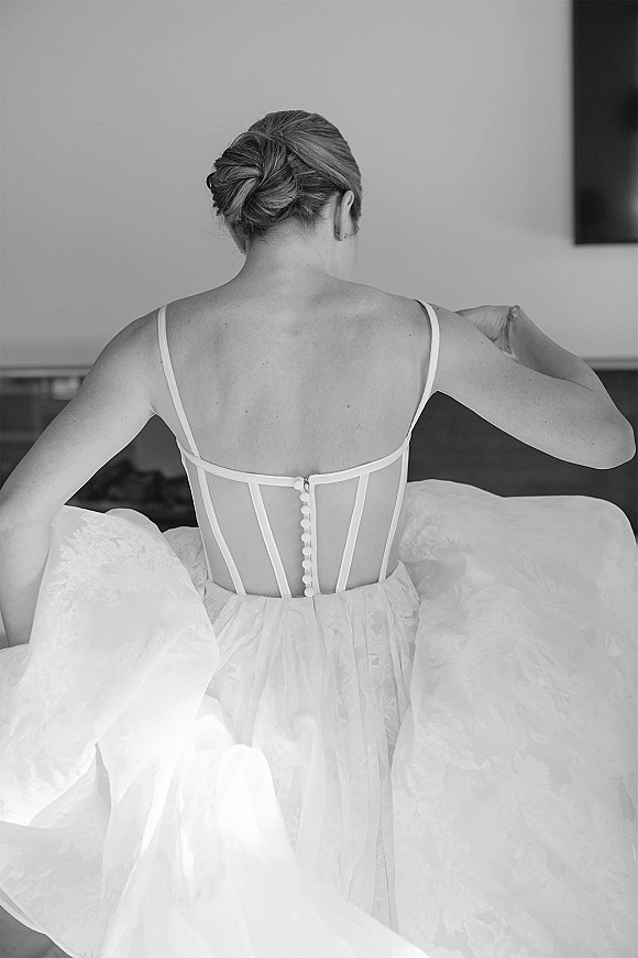 Bridal dress back with corset back wedding dress detailing, button row and spaghetti straps, bride in updo with earrings in an indoor room