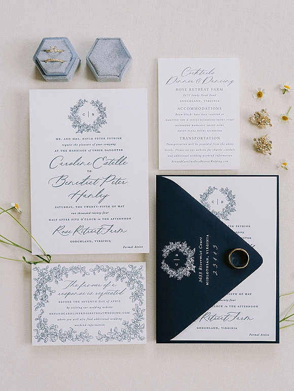 Invitation suite wedding invitation flat lay with blue and white cards, wax-sealed envelope, monogram crest, rings and earrings on linen