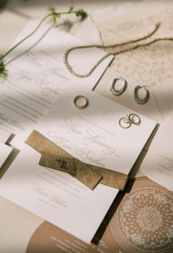 Invitation suite wedding invitation flat lay with envelopes, wax seal and ribbon, rings and jewelry on linen with a greenery sprig