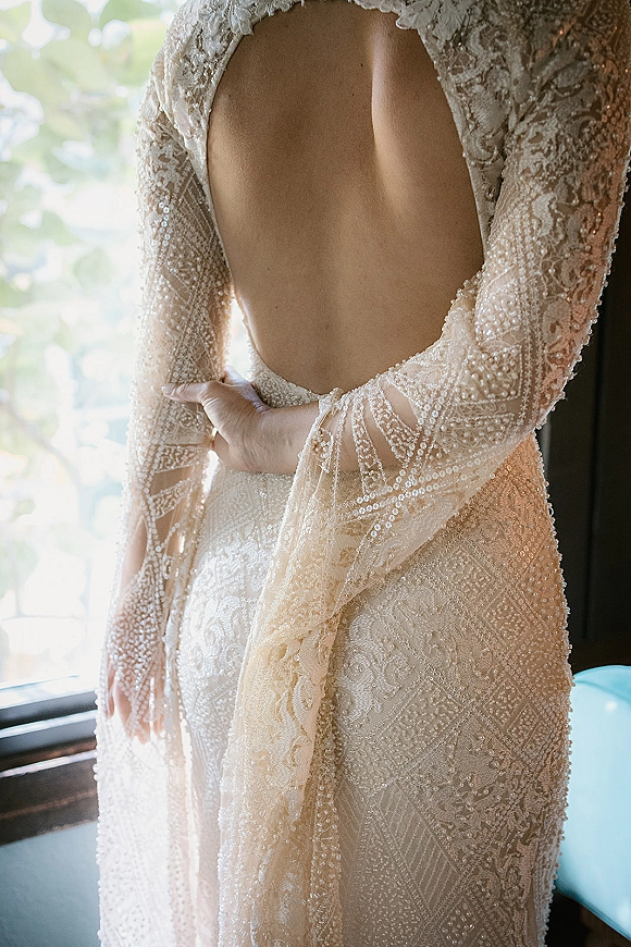 Wedding dress back with open back wedding dress beaded lace, long sleeves and embellished train, lit by soft window light indoors