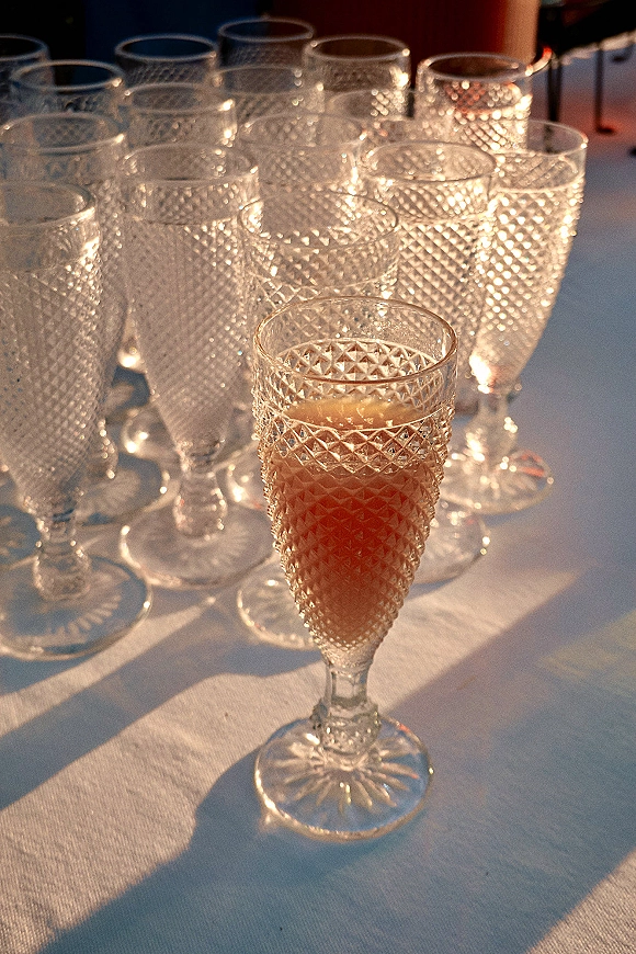 Champagne toast glasses filled with pink champagne in cut crystal champagne flutes on a white tablecloth in outdoor sunlight