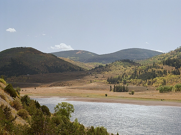 Mountain landscape with a mountain valley view as a winding river cuts through forested hills under a blue sky with drifting clouds