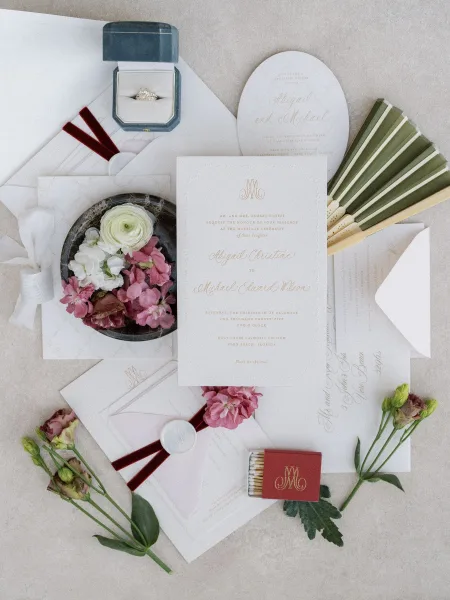 Wedding invitation suite featuring monogram wedding invitations and a wax seal, styled on a textured stone surface.